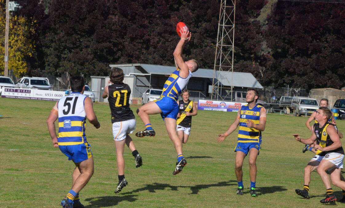 HIGH FLIER: MCUE's Nicholas McCormack marks strongly over Wagga Tigers'
Xavier Lyons (27) in Saturday's Riverina Football League game at Mangoplah.