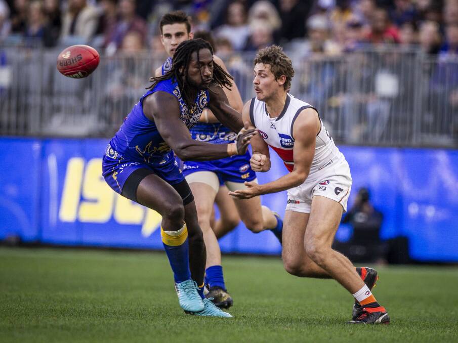 OUT: Harry Perryman fires a handball past West Coast's Nic Natanui in the game at Optus Stadium last Sunday. Picture: AAP