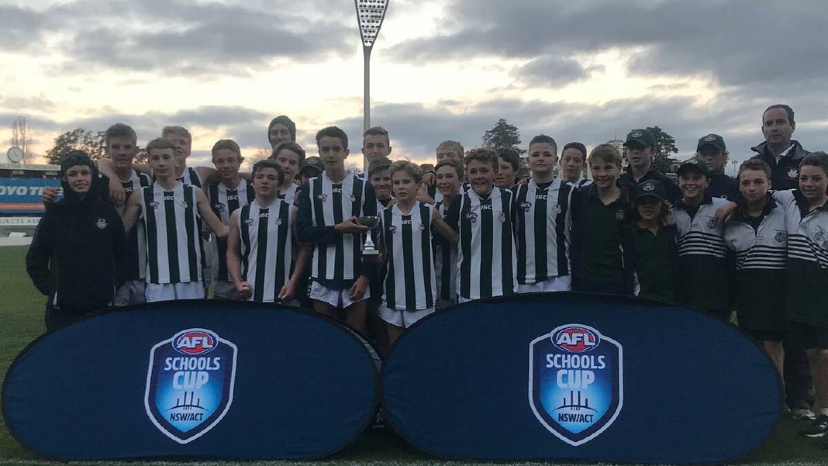 THREE STRAIGHT: The Riverina Anglican College's year seven and eight team celebrate their AFL Schools Cup win at Manuka Oval on Monday.
