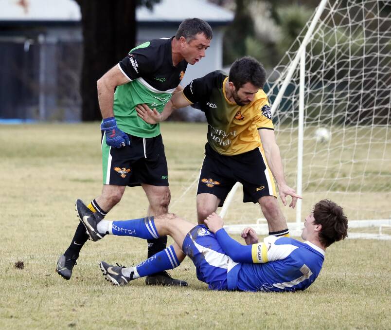 HEATED MOMENT: Tumut keeper Matt Casey and Ethan Kass take exception to the challenge of Tolland captain Nick Tsipiras at Henwood Park on Sunday. Picture: Les Smith
