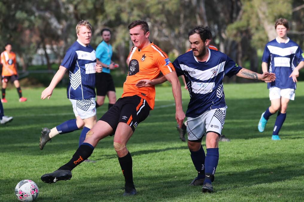 FIRST TOUCH: Wagga United's Matthew Crawford gets the ball away despite close attention from Young's Bradley Galvin in the Pascoe Cup game at Rawlings Park on Sunday. Picture: Emma Hillier