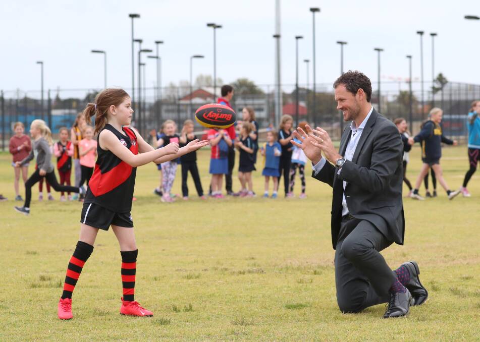 HANDS ON: Eight-year-old Essendon fan Maddie Pilon shows off her handballing skills to AFL NSW-ACT chief executive Sam Graham at Bolton Park on Wednesday. Picture: Les Smith