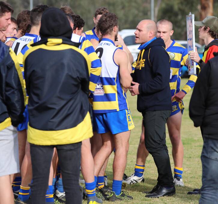 Sidelined MCUE coach Jeremy Rowe talks to his players at quarter time of Saturday's win over Narrandera.
