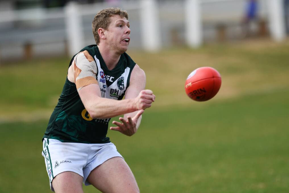DAY OUT: Coolamon's Joe Redfern fires off a handball against Griffith on Saturday.