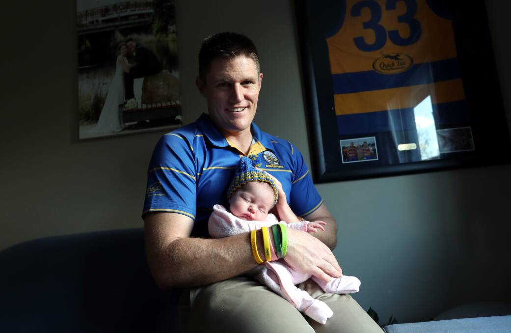 FAMILY MAN: Mangoplah-Cookardinia United-Eastlakes coach Travis Cohalan with two-week old daughter Ivy at home in Wagga. Picture: Les Smith
