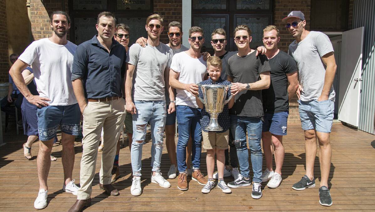 SPECIAL VISIT: Hawthorn players show off one of their premiership cups at the re-opening of the Temora Hotel on Saturday. Picture: Ashton Taylor