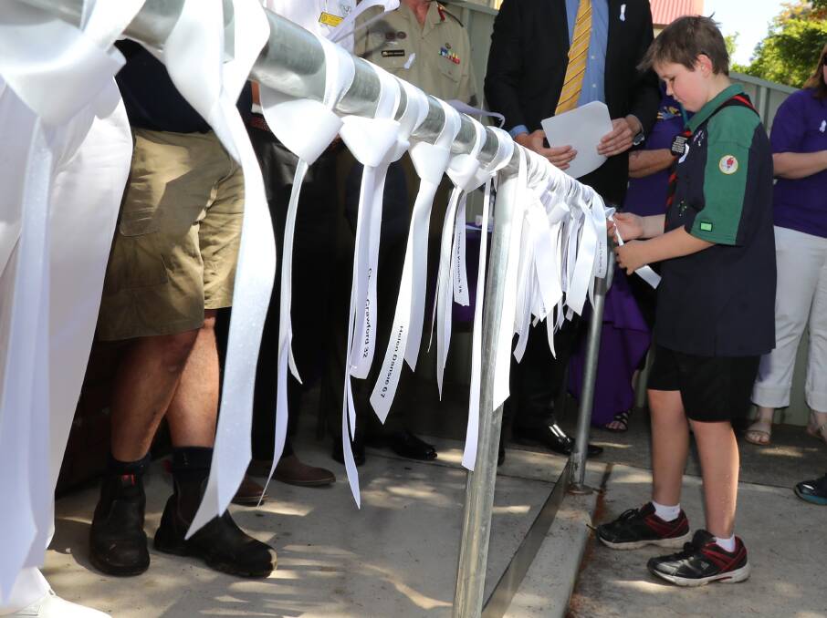 Nicholas Anderson from First Kooringal Scouts ties a symbolic ribbon against domestic violence at the White Ribbon Day ceremony in Wagga in 2017.