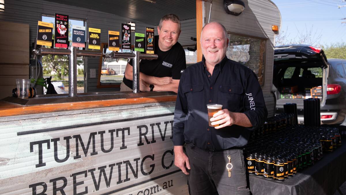 Tumut River Brewing Company co-founder Tim Martin and Junee Licorice and Chocolate Factory's Neil Druce share a beer at a pop-up fundraiser for the brewery on Friday. Picture by Madeline Begley