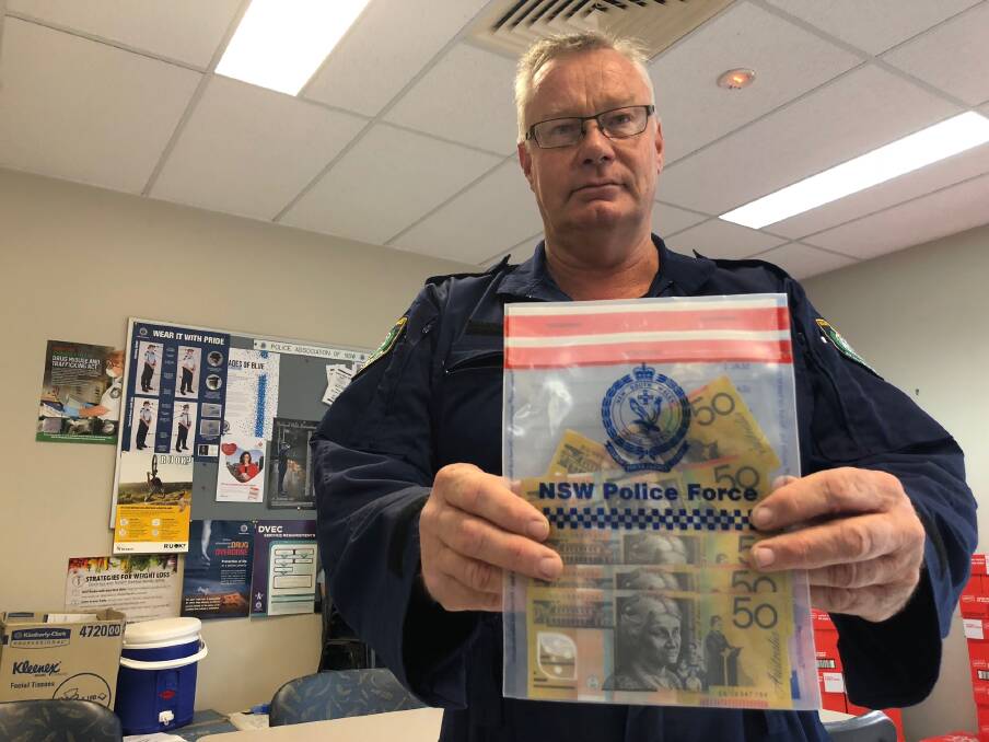 Senior Constable Alan Cope with counterfeit cash discovered in Griffith last week. Picture: Jacinta Dickins