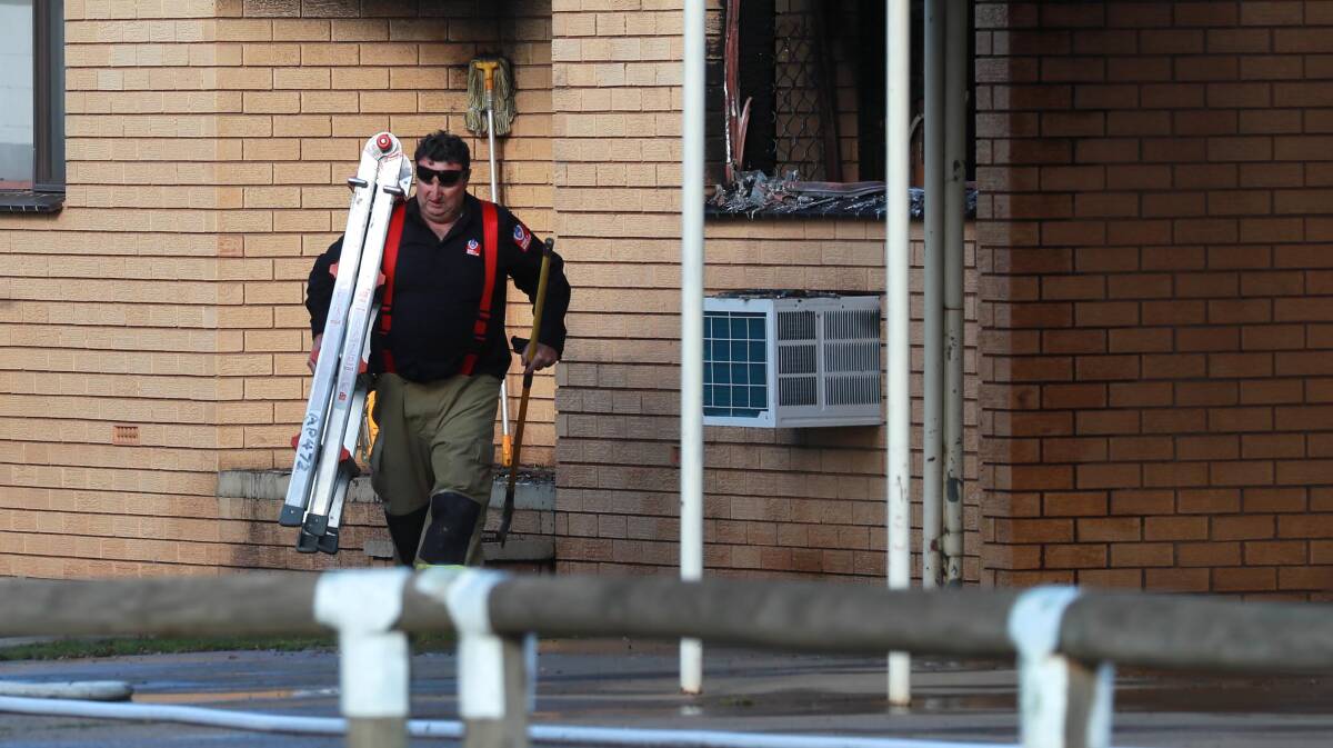 JOB DONE: A firefighter carries equipment from a Bulolo Street unit after a fire on Thursday. Police have charged a 22-year-old man over the incident. Picture: Les Smith