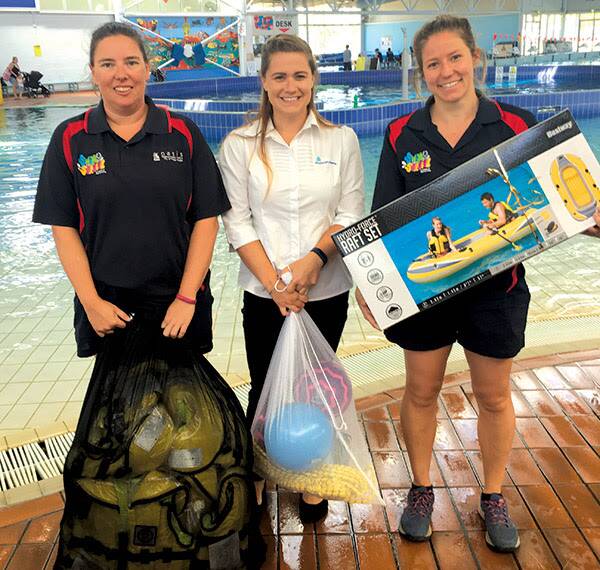 IN THE POOL: The Royal Life Saving Society’s Ash Carter (centre) presents Oasis staff Nicole Peckham (left) and Jenee West with an open water survival program training kit. Picture: Wagga City Council