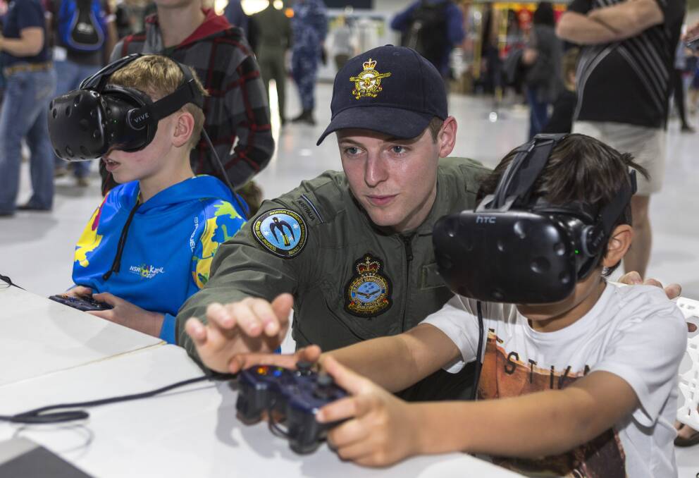 Levi Piivainen tries the RAAF virtual reality simulator with the help of Pilot Officer James Davies at the 2018 Temora Warbirds Downunder. Picture: Corporal David Gibbs