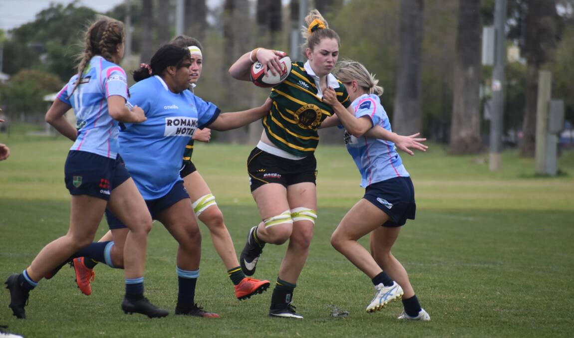 POWERING ON: Liz Young tries to break out of a tackle attempt as Ag College won through to the Southern Inland grand final with a 41-7 win over Waratahs at Leeton No.1 Oval on Saturday. Picture: Liam Warren