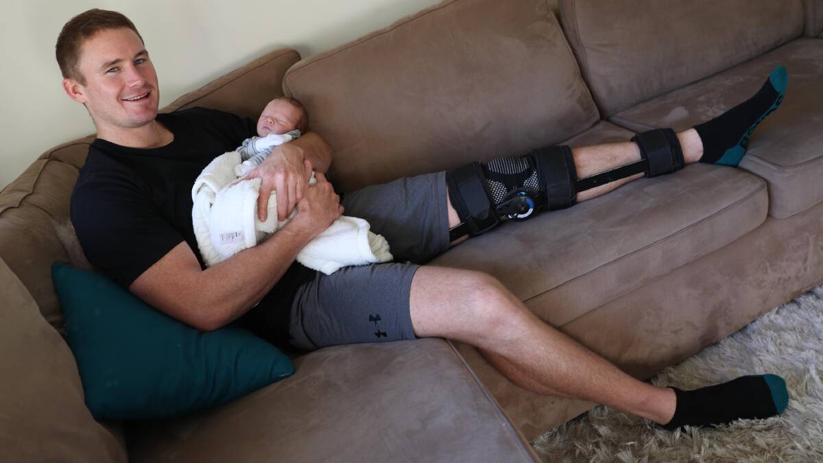 Nick Skinner nursing a knee injury and newborn son Joey in May 2018.