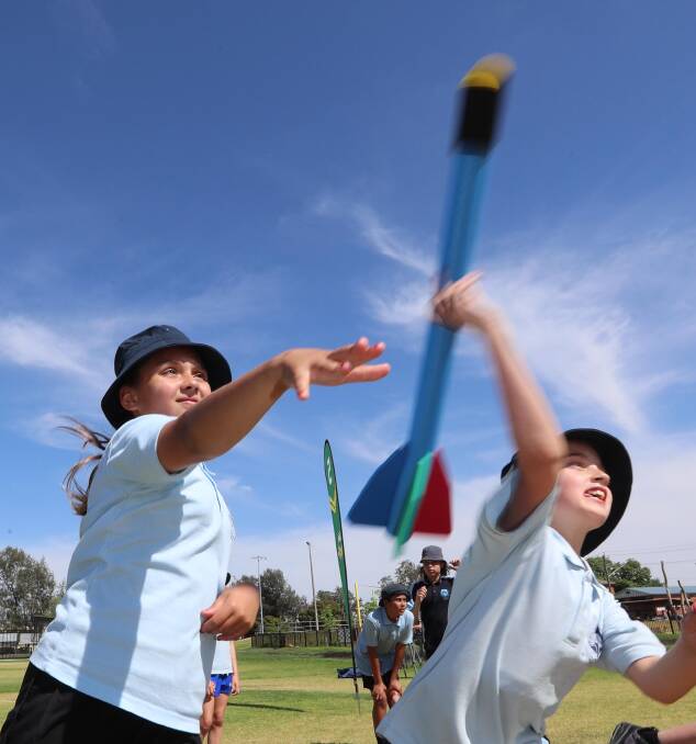 NEW SKILLS: Ashmont Public students Shaelah Black, 11 and Kayla Van Beers, 10, taking part in the NRL's Walanmarra Gundyarri Cultural Day at Bolton Park on Thursday. Picture: Les Smith