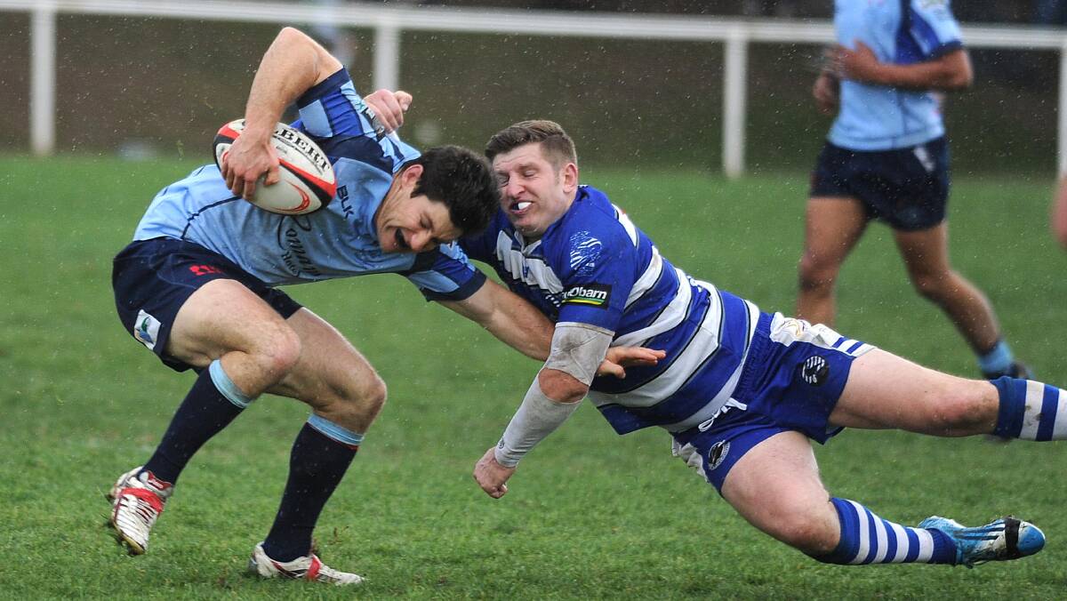 SLIPPERY CONDITIONS: Waratahs halfback Sam Hobbs tries to duck under a tackle from Wagga City fullback James Curgenven on Saturday.