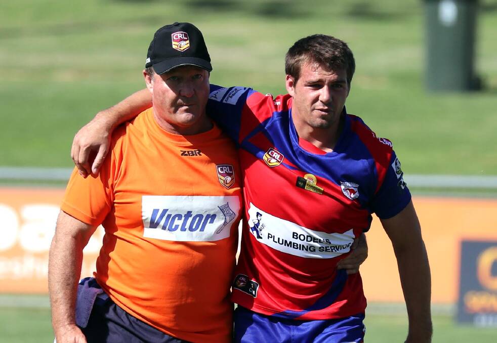 HELPING HAND: Kangaroos coach Glenn Dumbrell is assisted from the field after injuring his ankle early in the win over Young on Saturday. Picture: Les Smith