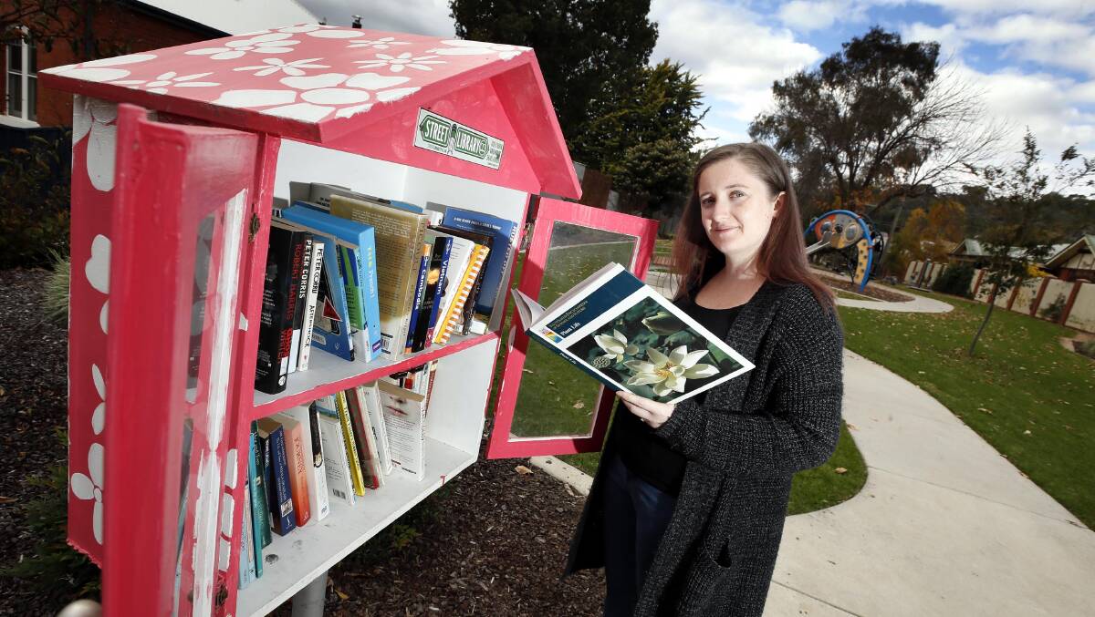 GOOD FIND: Emma Eden has found some great books at one of the Street Library points at Flinders Street playground. Picture: Les Smith