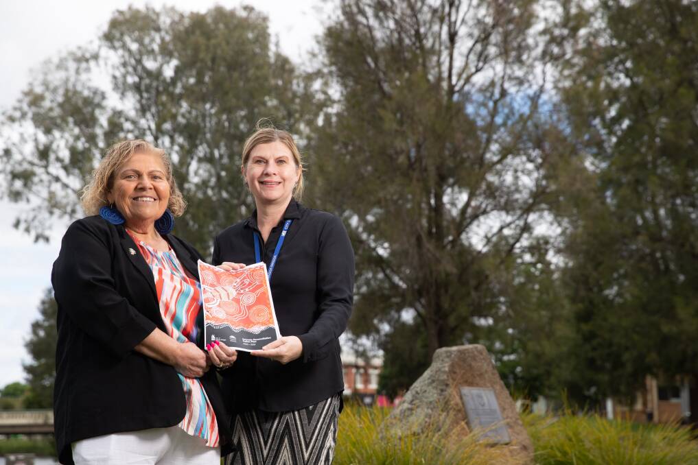 Wiradjuri elder Aunty Mary Atkinson and Wagga City Council community services director Janice Summerhayes holding the 2022-2024 RAP which shows Indigenous work by First Nations residents. Picture by Madeline Begley 
