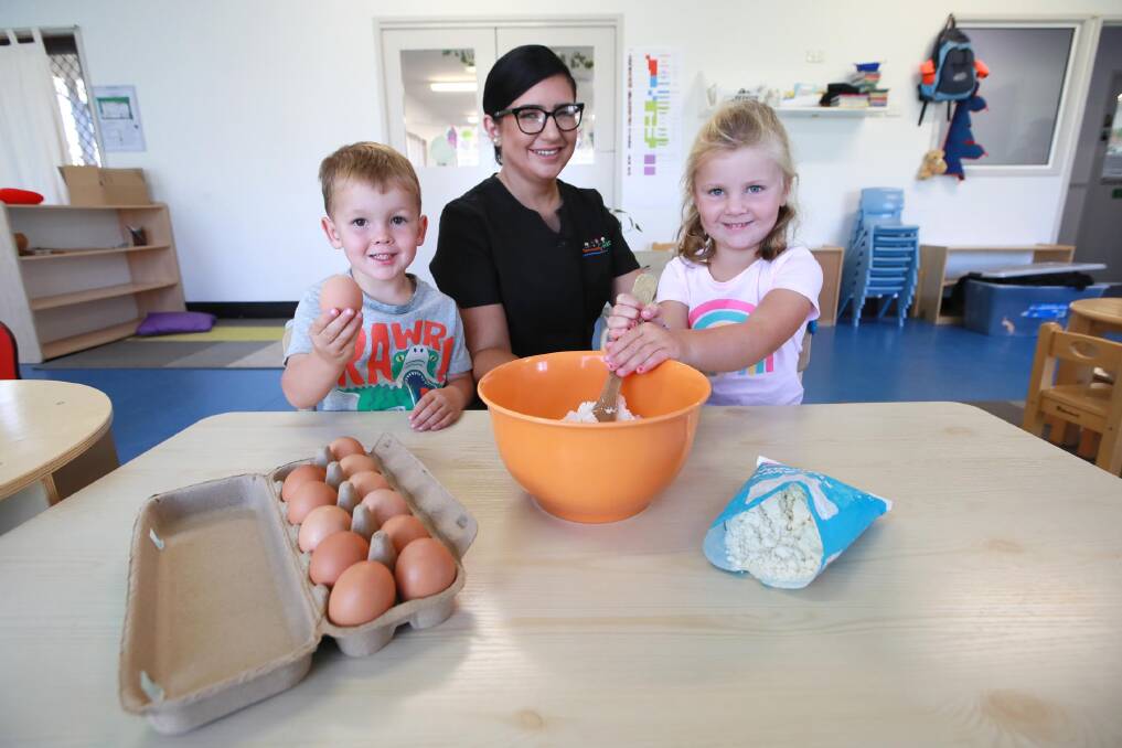 CRACK THE EGG: Gemma McKenzie teaches Euan Nicholas, 3, and Grace Drum, 4, how to measure items and create baked goods. Picture: Les Smith 