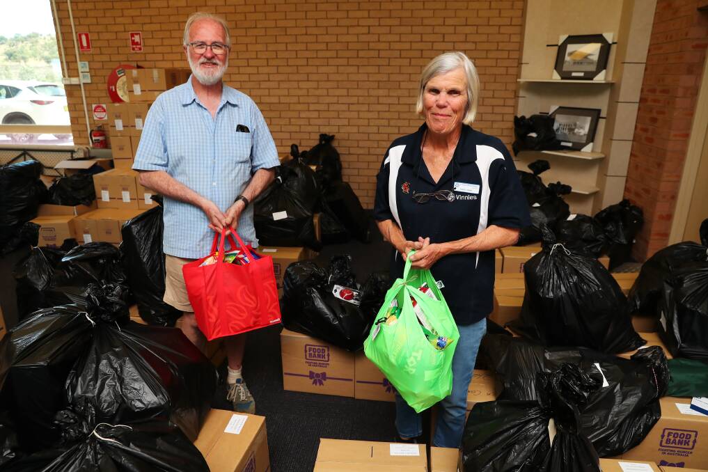 HELPING HAND: Warwick Grundy and Maryanne Loughlin help pack the black bags full of toys to give some children a Christmas morning surprise. Picture: Emma Hillier 