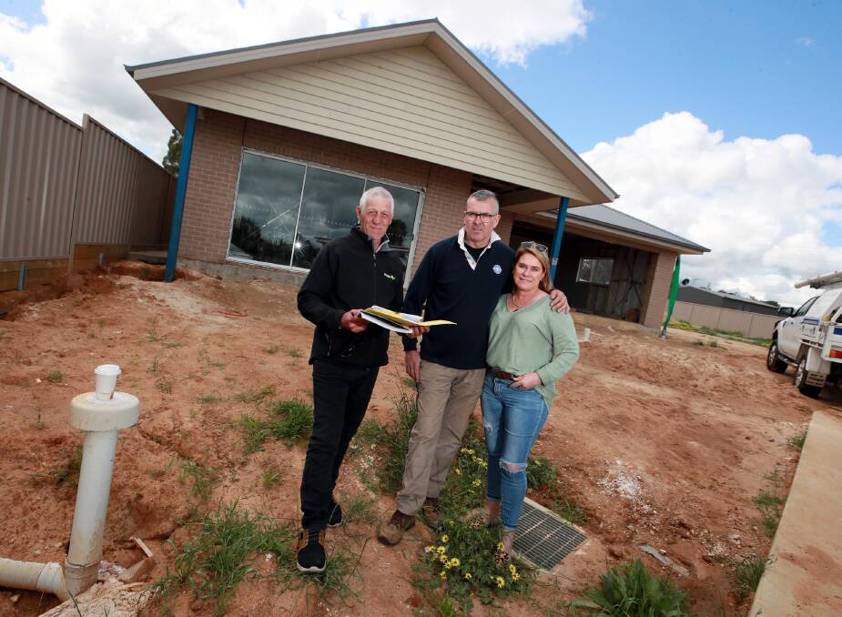 IMMENSE GRATITUDE: Andrew White with Geoff and Cathy Reid in front of the house that is starting to take shape in Boorooma. Picture: Les Smith 