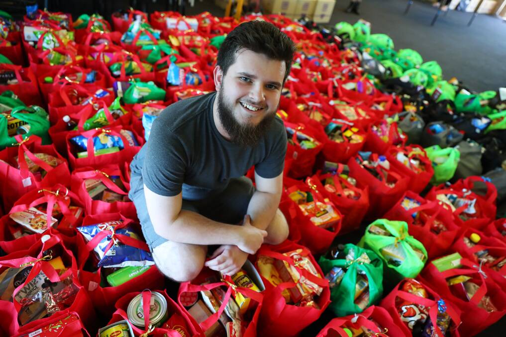 CHRISTMAS COLOURS: Volunteers, including Nicholas Marinac, have been hard at work packing hampers to distribute among families throughout Wagga. Picture: Emma Hillier 