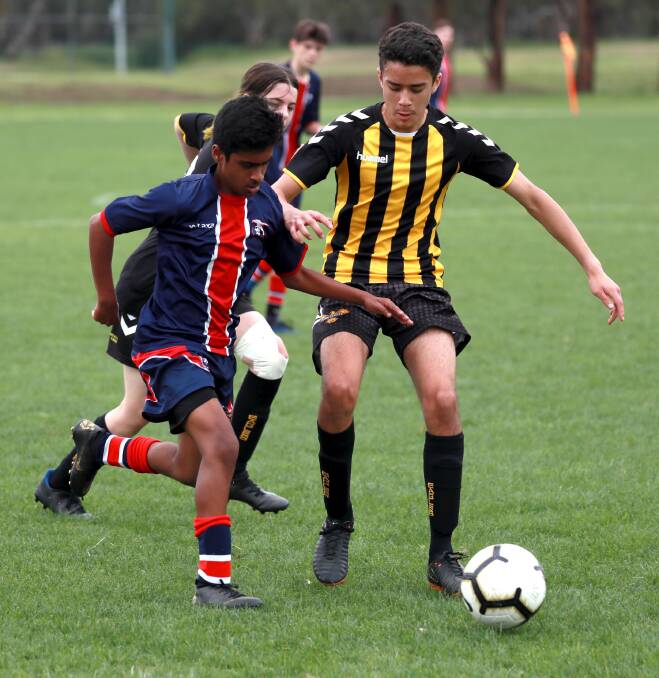 GRAND FINAL AWAITS: Tumut's Carlos Rodriguez (right) tries to hold off Nidhin Sebastian from Henwood Park in their under 14 preliminary final. Tumut Black won the right to take on Wagga United in this weekend's grand final. Picture: Les Smith