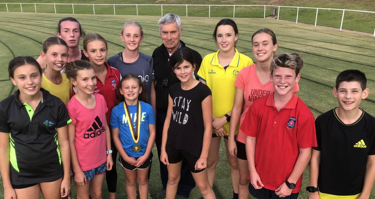 MASTER AT WORK: Coach Mark Conyers is surrounded by some of his keen runners (from left) Holly Roach, Ruby Doherty, Matt Moffat, Imogen Metcalfe, Charlotte Priest, Myer Mescia (with Mark's Masters gold medal), Harriett Priest, Ella Hughes, Zara Hamilton, Annabel Roach, Henry Keogh and Mason Mescia. 