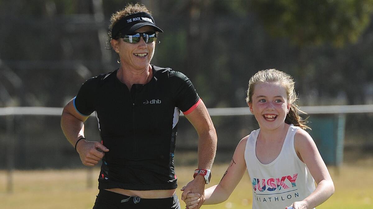 HAPPY DAYS: Briony Mazzocchi and daughter Ally, 8, cross the finish line in The Rock triathlon 2018 on Sunday. 