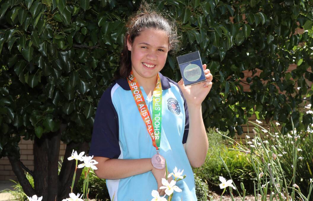 MORE MEDALS: Jasmine Ferguson, 12, wearing her bronze medal from nationals and holding up further recognition from Sacred Heart Primary of her athletics achievements. PIcture: Les Smith