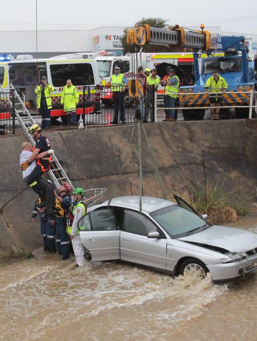 LUCKY ESCAPE: A driver is rescued from a stormwater drain after he ploughed through the fence at the Bunnings roundabout. Picture: Les Smith 