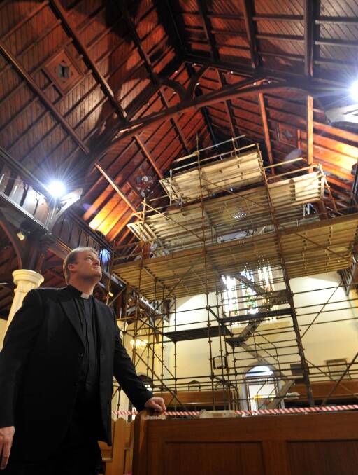 UNHOLY SPLIT: St John's Anglican Church priest Father Michael Armstrong looks at the century-old wooden beams which have been split, causing the church to be closed. 