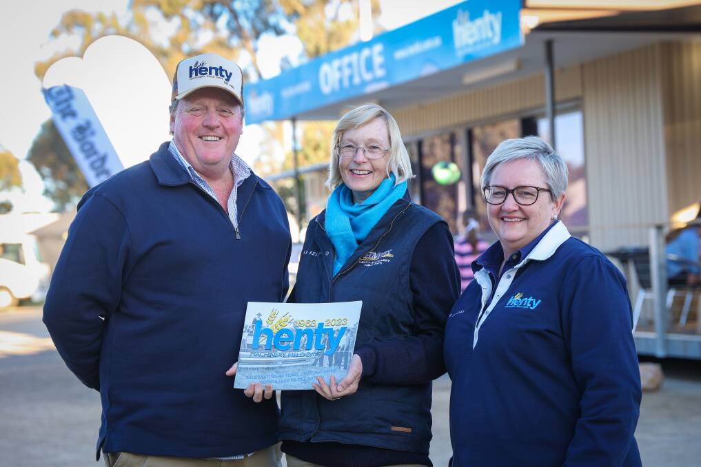 Country to the core ... Henty Machinery Field Days chairman Nigel Scheetz, media manager Kim Woods, HMFD chief executive Belinda Anderson pictured in 2023 with the book celebrating the event's 60 years of history written by Ms Woods. Picture supplied