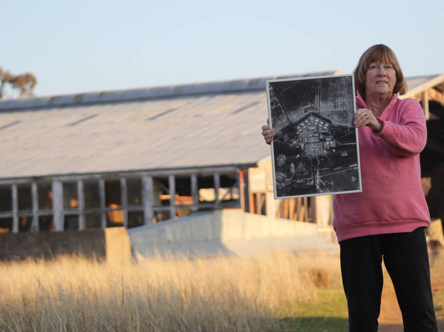 History in the blood and soil: Jenny Lewington holds an aerial view of the former Uranquinty Migrant Centre, while standing in front of the old mess hall. 