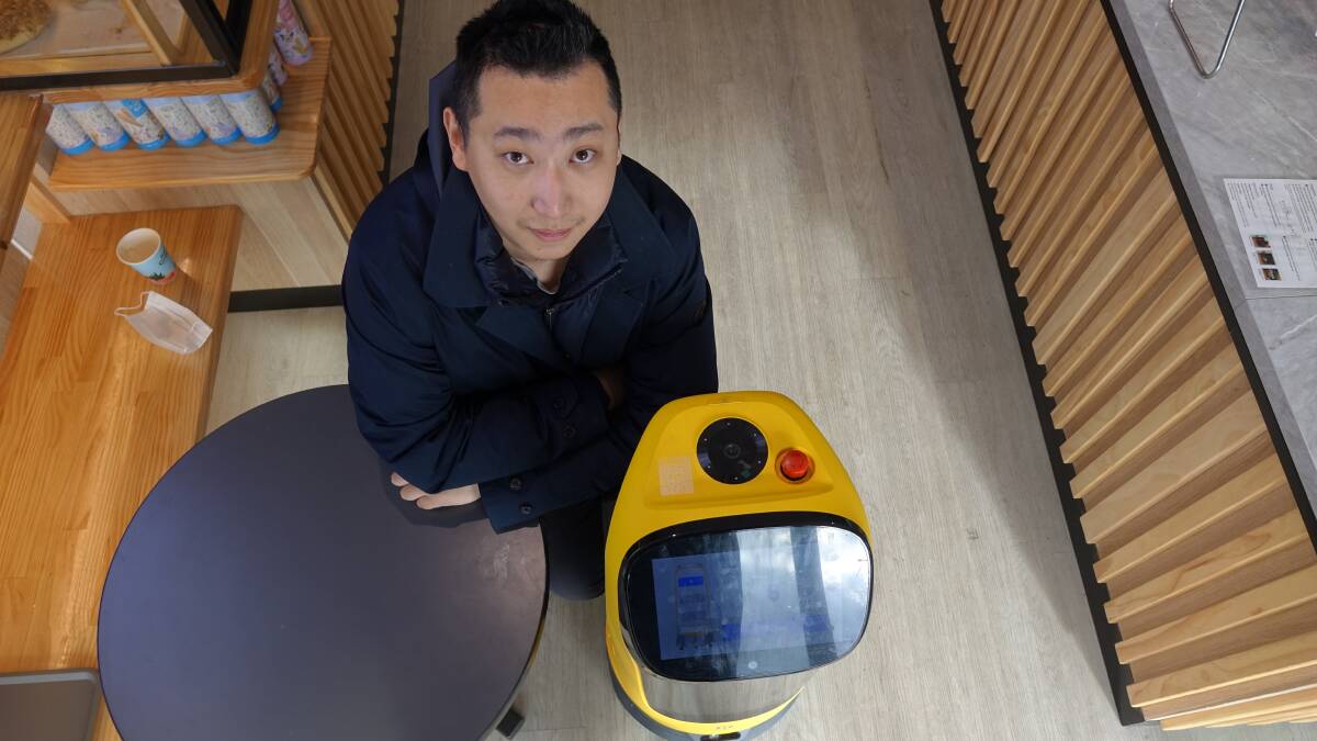 It delivers, it talks - it asks you if you need help. Jack Wang and the waiter robot. Picture: Steve Evans