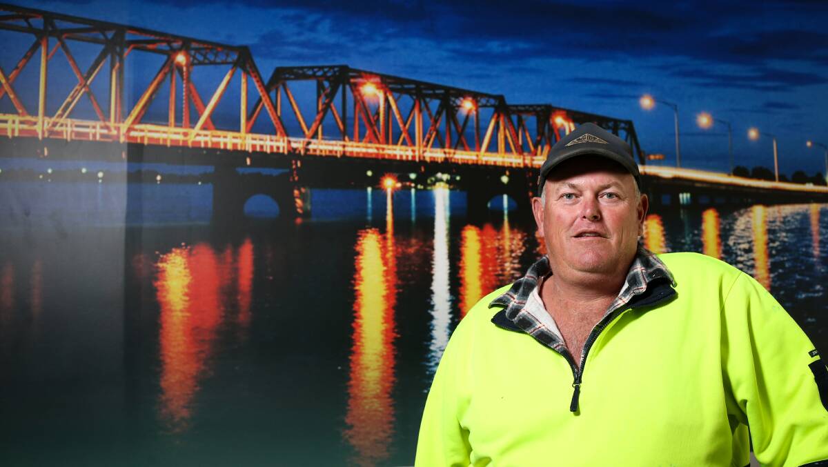 Cross over crossing: Builder Andrew Kennedy at his Mulwala office in front of a picture of the bridge which spans the nearby lake into Yarrawonga.