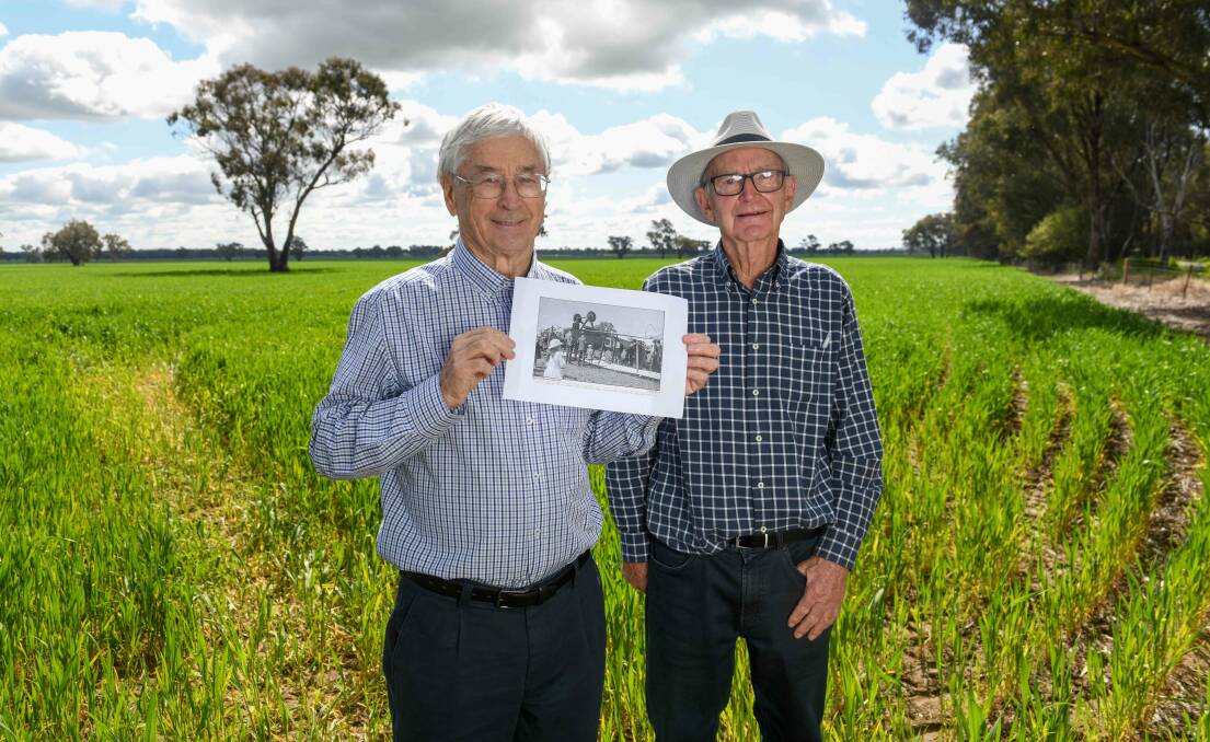 Dick Smith and Neville Lowe standing in front of the paddock where a forced landing occurred in August 1920. Mr Smith is holding a copy of the plane involved which flipped upside down after touching down. Picture by Tara Trewhella