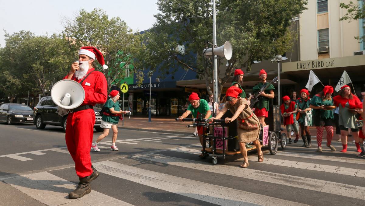 Elves crossing: Santa leads his elves and makeshift 'sleigh' across a Dean Street pedestrian point. Picture: TARA TREWHELLA