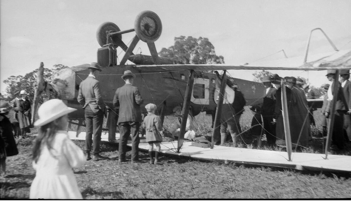 Townsfolk from Culcairn and surrounds gather to look at the upside down de Havilland plane which landed in a paddock not far from the railway south of town. Picture from the Australian War Memorial