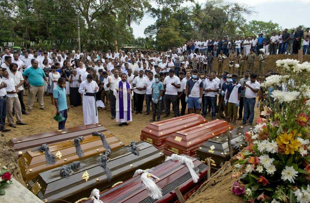 MOURNING: A priest conducts religious rituals during a mass burial for bomb blast victims in Negombo, Sri Lanka on April 24. Picture: AP Photo/Gemunu Amarasinghe