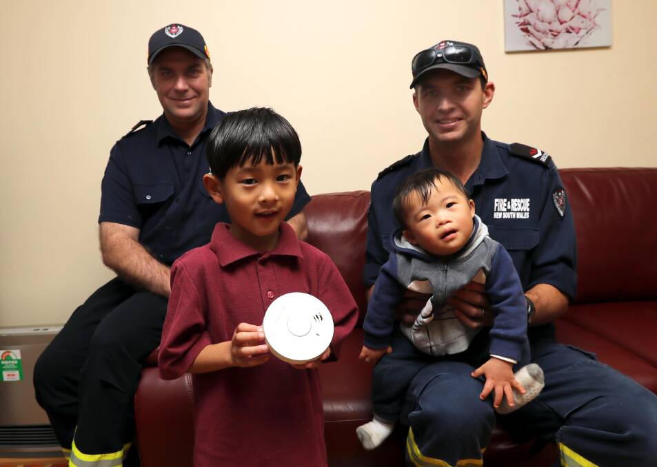 NEW FRIENDS: Senior firefighter Lee Hyde with firefighter Joel Sim and the Dashi children, Michael, 5, and Isaac, 14 months. Picture: Les Smith 