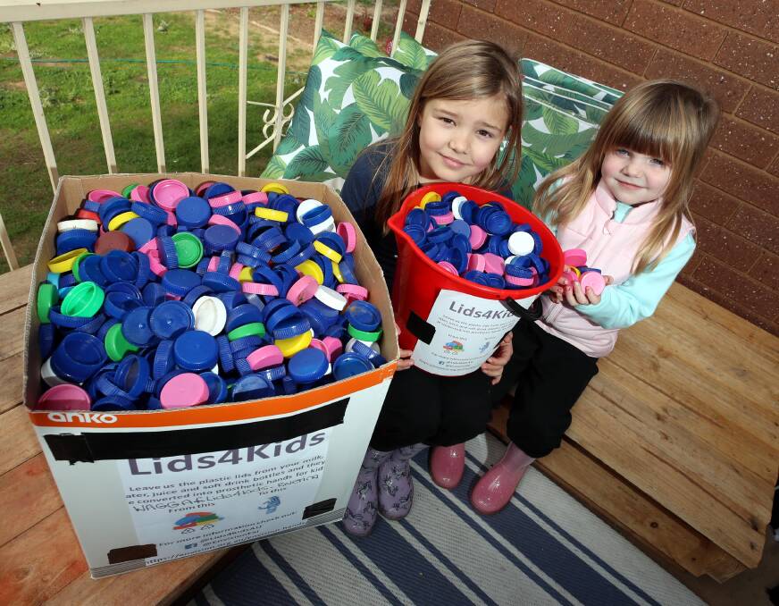 GOOD CAUSE: Ruby Thompson, 8, and her sister Olivia Thompson, 5, with the caps collected by their mum for Lids4Kids. Picture: Les Smith 