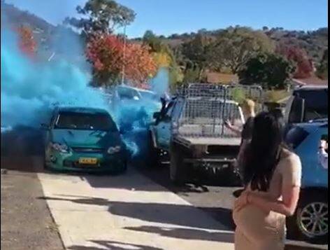 A pregnant woman watches on as the gender of her baby is revealed with blue smoke from a burnout. The driver received $1700 in fines and a disqualified licence for the stunt. 