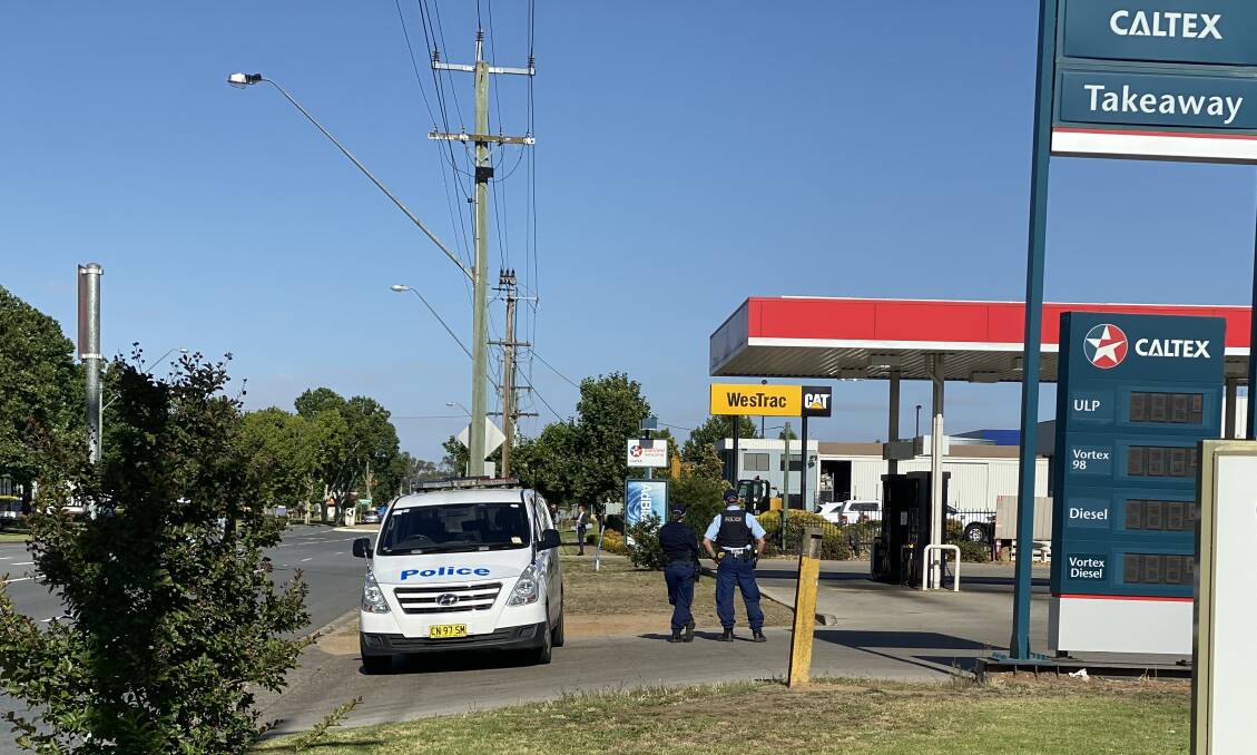 Police officers cordon off the entry and exit of the service station as forensic examinations are conducted. 