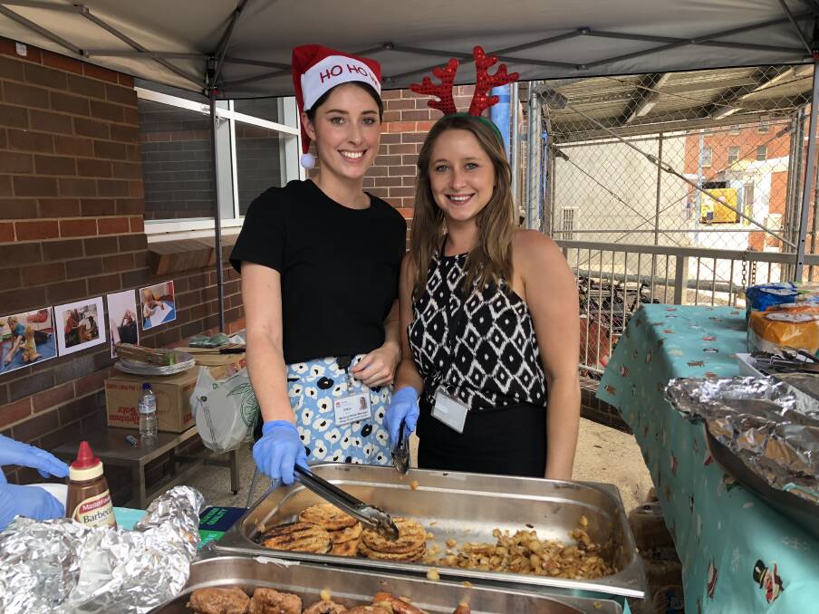 SPREADING CHRISTMAS CHEER: Jillian Green and Sophie Watt man the food station at the party. Picture: Annie Lewis 