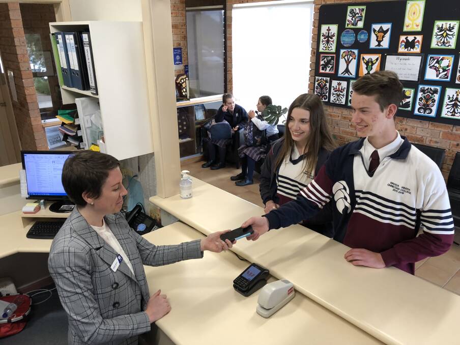 HANDOVER: Wagga Christian College's Jarrad Holmes, 18, and Karabella Cattanach, 17 hand-in their phones to admin officer, Katelyn Weston, to take a break from the technology. Picture: Andrew Pearson 
