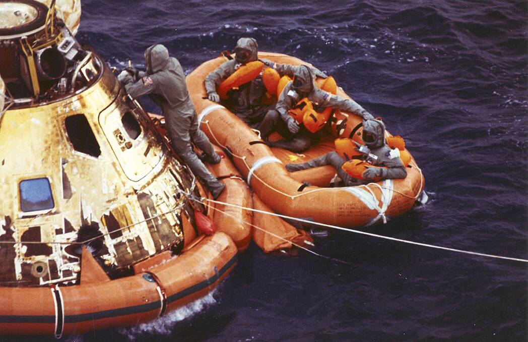 The Apollo 11 spacecraft hatch as astronauts Neil Armstrong, Michael Collins, and Buzz Aldrin, Jr., await helicopter pickup from their life raft after splashdown in the Pacific Ocean.