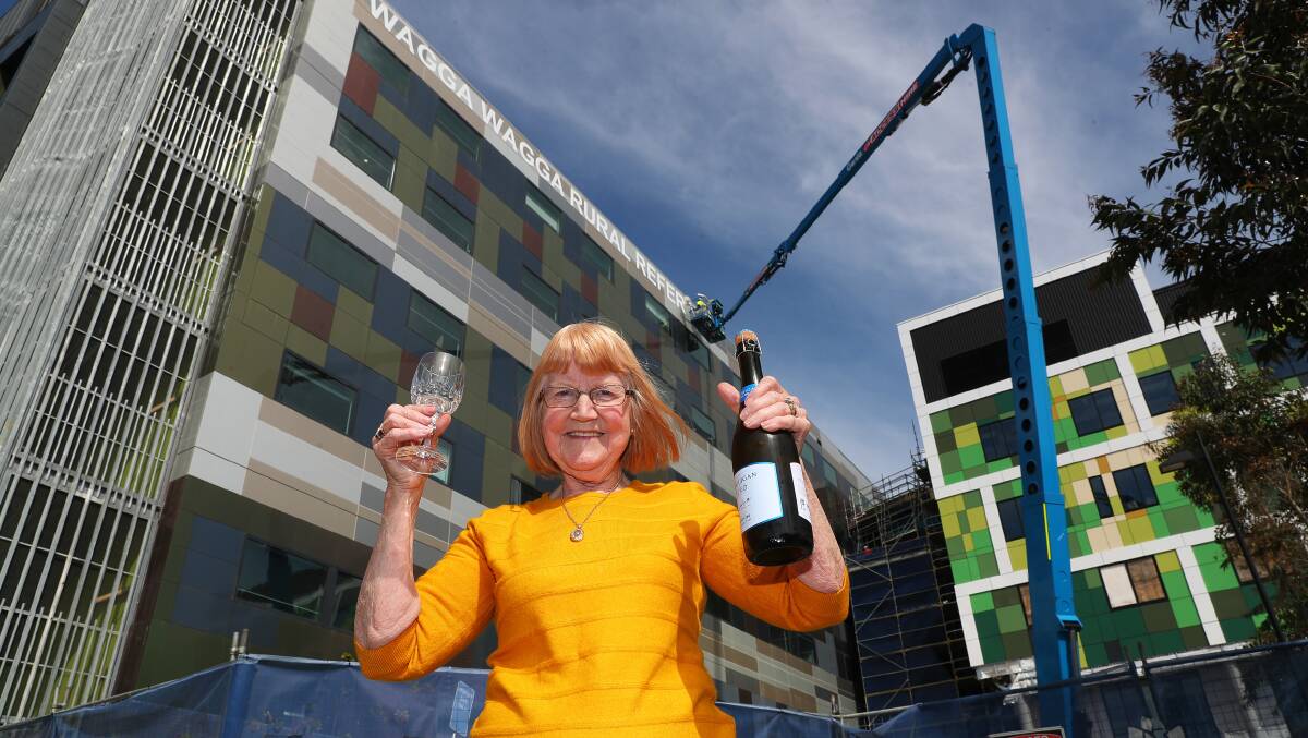 BIG WIN: Wagga's Catherine Pierce celebrates with champagne as the Wagga Wagga Rural Referral Hospital sign is taken down after years of fighting for its removal. Picture: Emma Hillier 