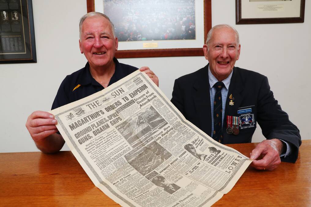 Wagga RSL Sub-Branch president David Gardiner and Arthur Briggs holding a newspaper from August 15, 1945. Picture: Emma Hillier